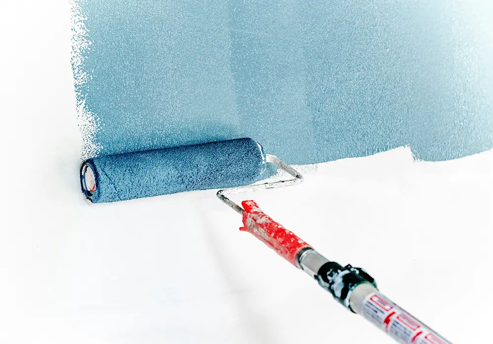 A paint brush painting walls and ceiling of a bathroom