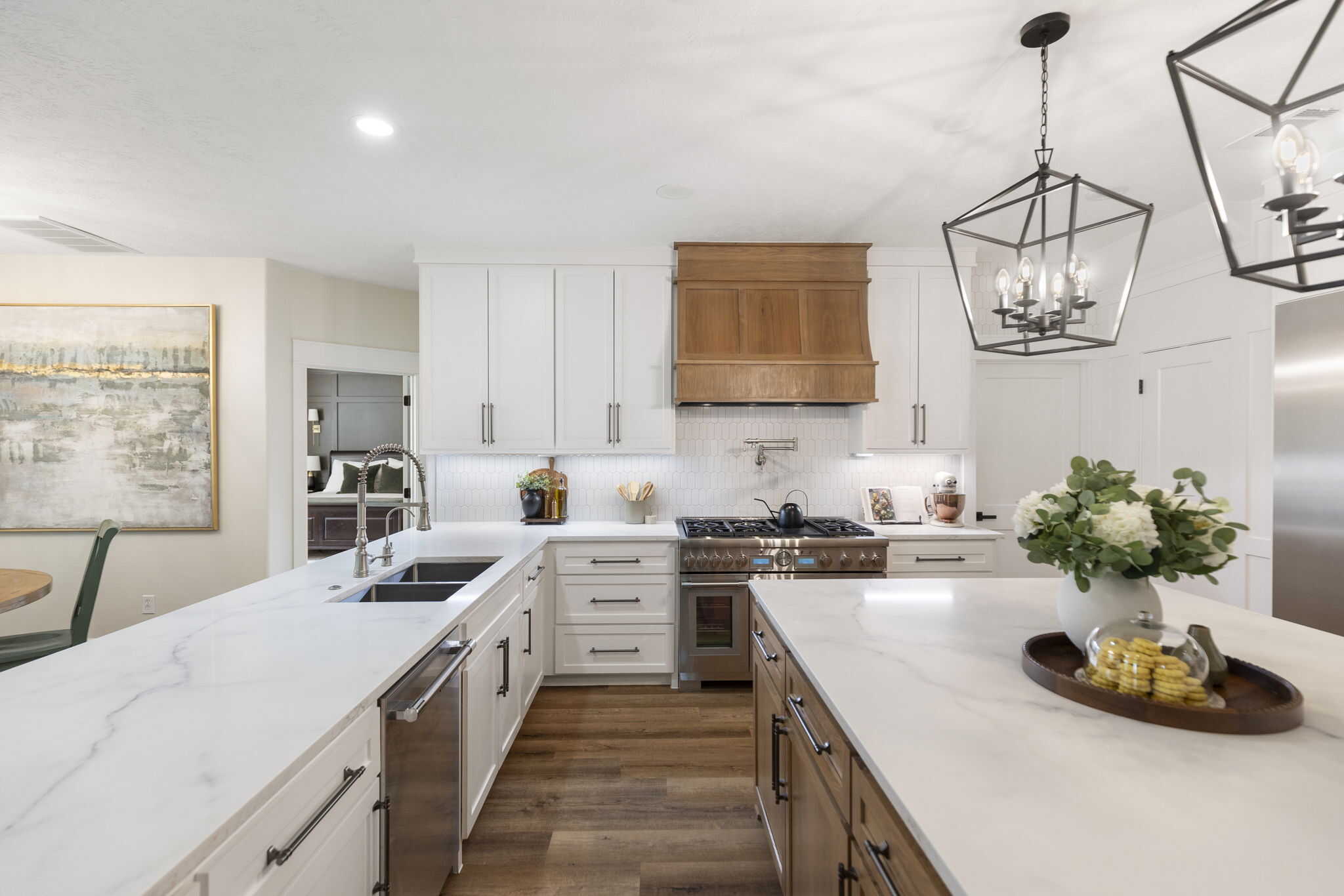 Bright kitchen with white cabinets, wood range hood, large island, and modern pendant lighting