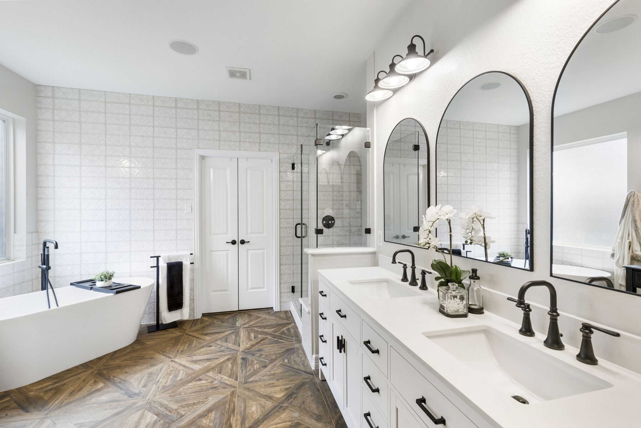 Luxury bathroom design featuring geometric tile floors and black hardware Elegant bathroom with double vanity, modern fixtures, and freestanding tub