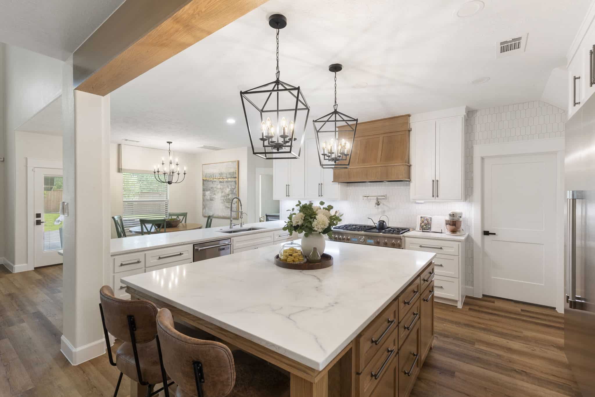 Contemporary kitchen design with marble island and elegant lighting fixtures Modern kitchen with large marble island, wooden accents, and black pendant lighting