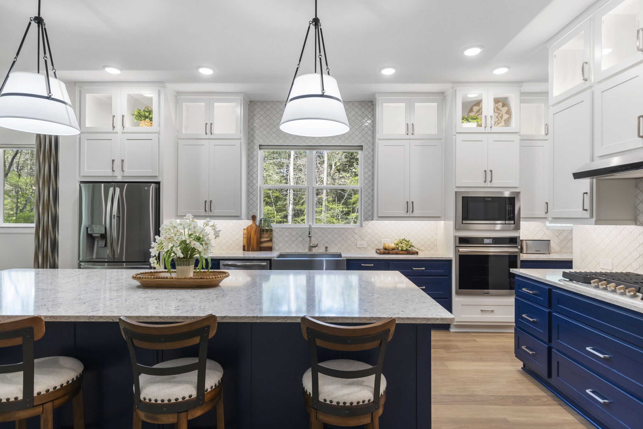 Modern kitchen with white and navy blue cabinets, large island, and pendant lighting