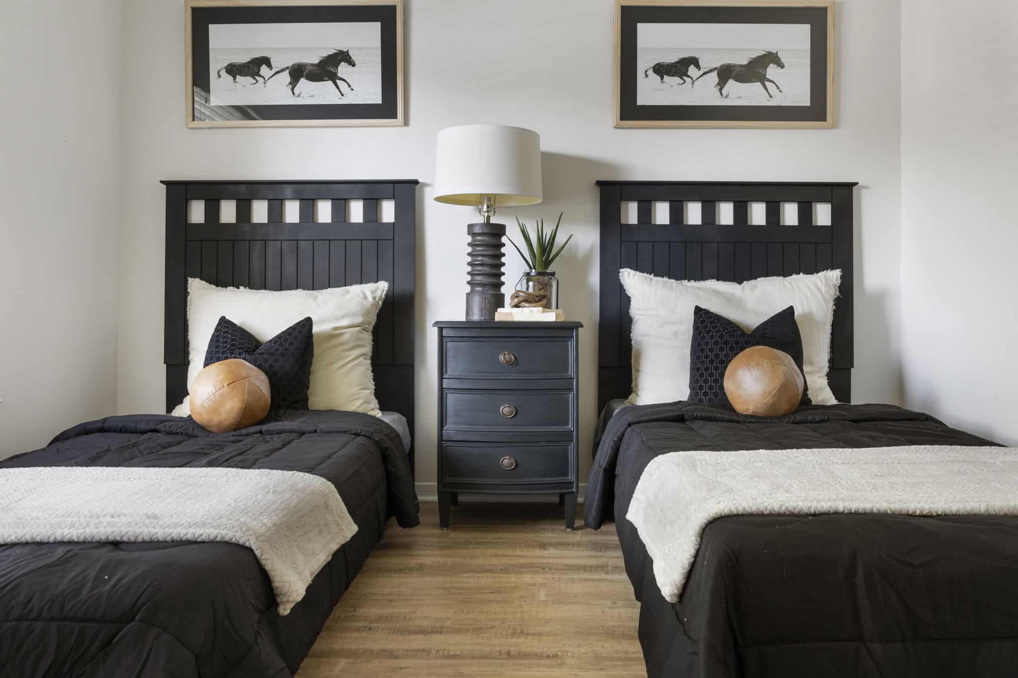 Stylish twin bedroom design with coordinated decor and warm wood flooring Modern twin bedroom with black headboards, neutral bedding, and wooden accents