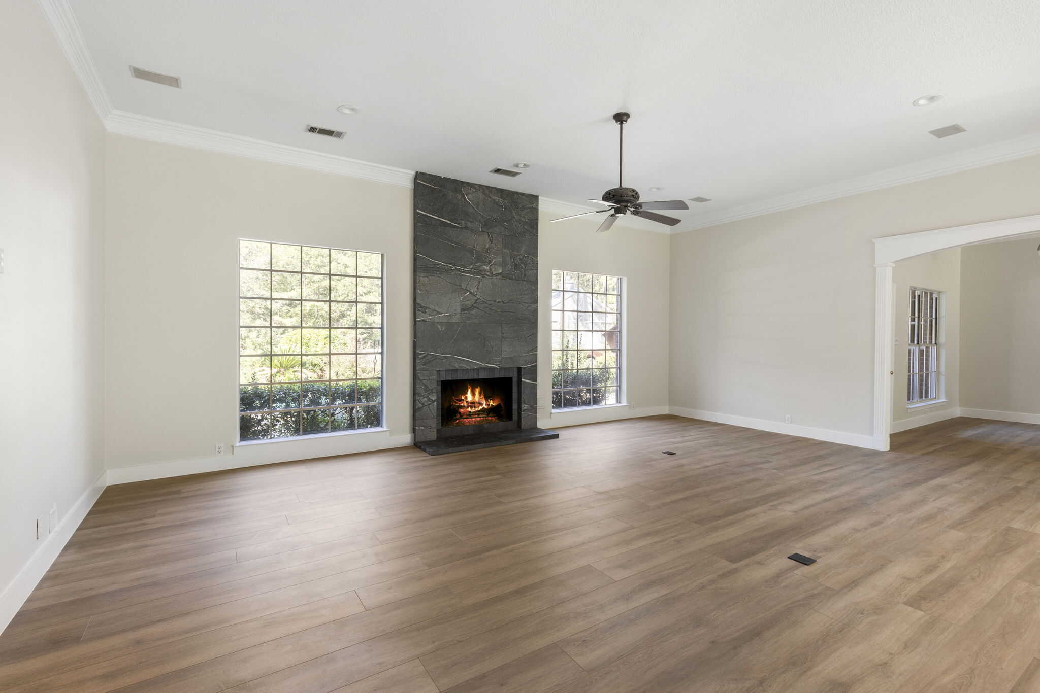 Bright living room interior with wood flooring and stone fireplace Spacious living room with hardwood floors and a fireplace feature wall