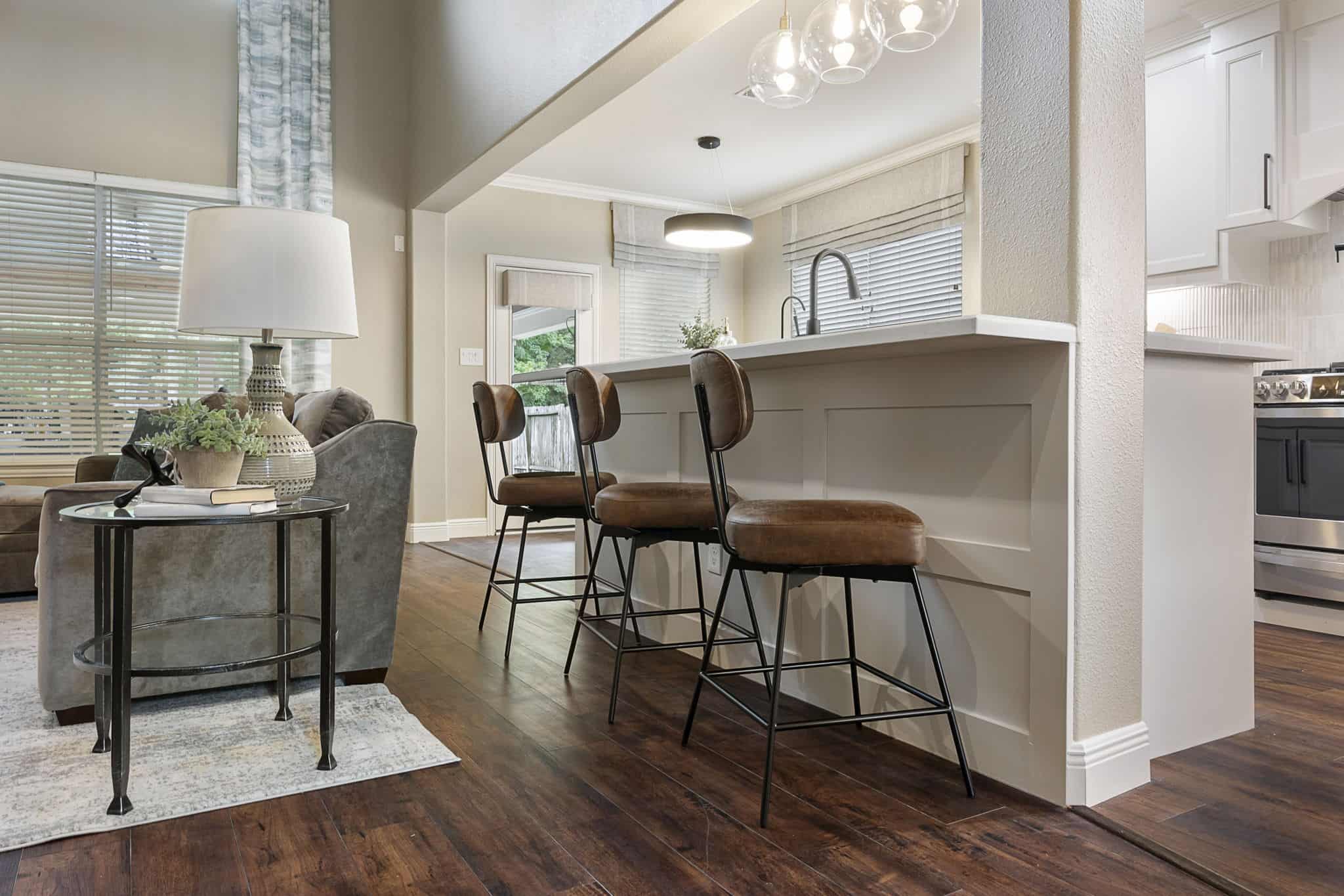 Modern home interior with inviting seating area and breakfast bar Cozy open-concept living area with kitchen island and bar stools