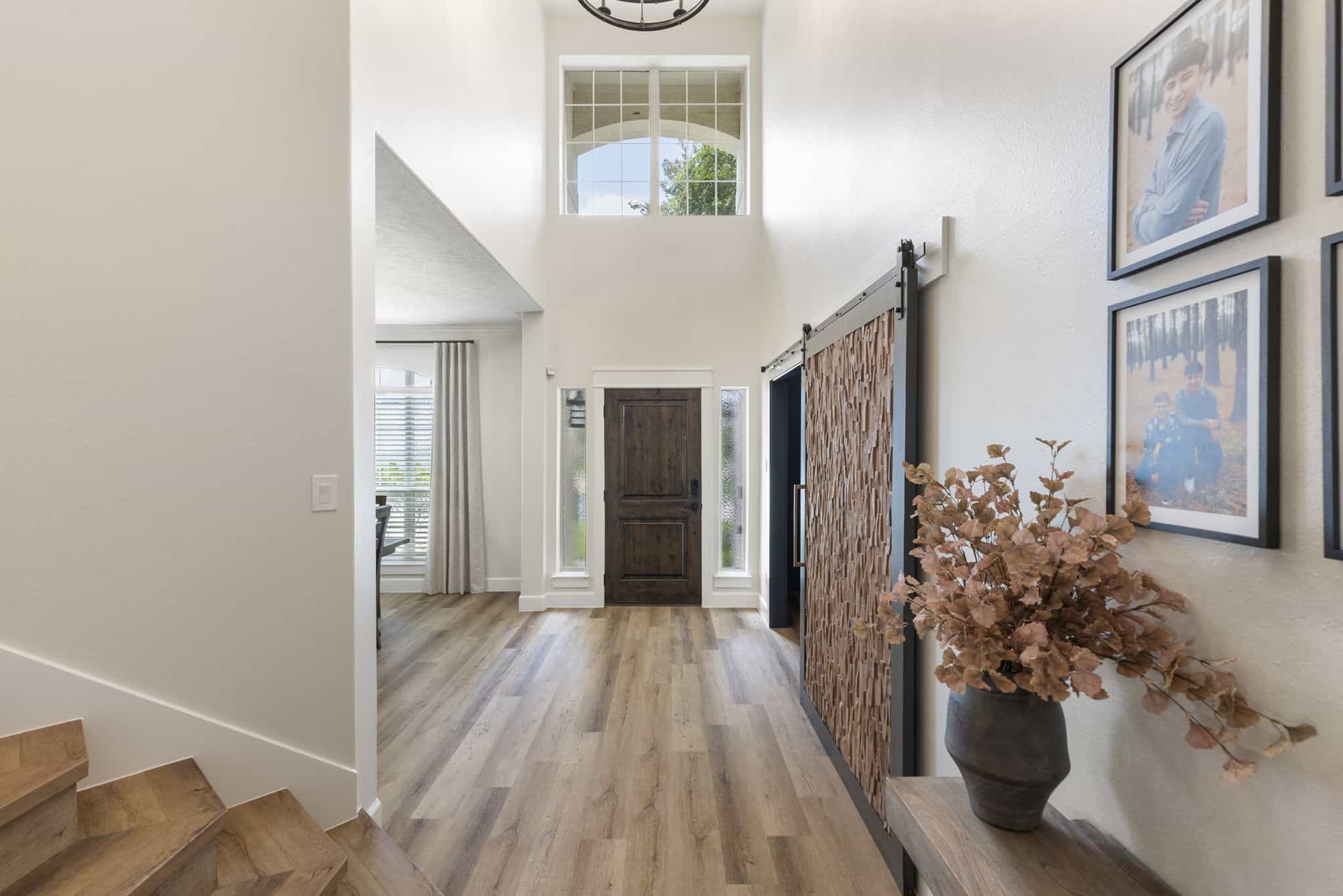 Bright home entrance with natural light and wood accents Modern entryway with wooden floors, front door, and decorative wall art