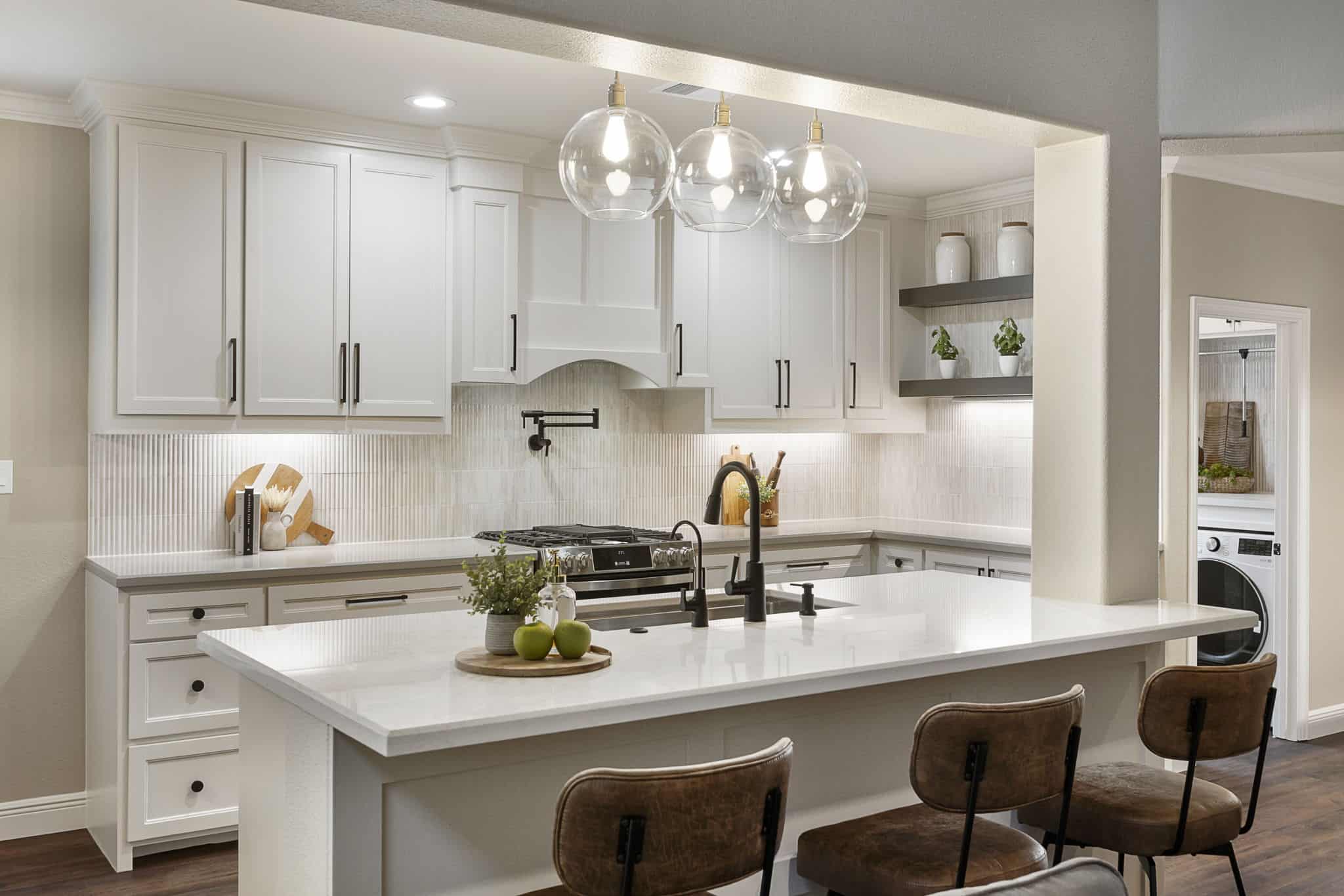 Modern kitchen with white cabinets, island seating, and glass pendant lights