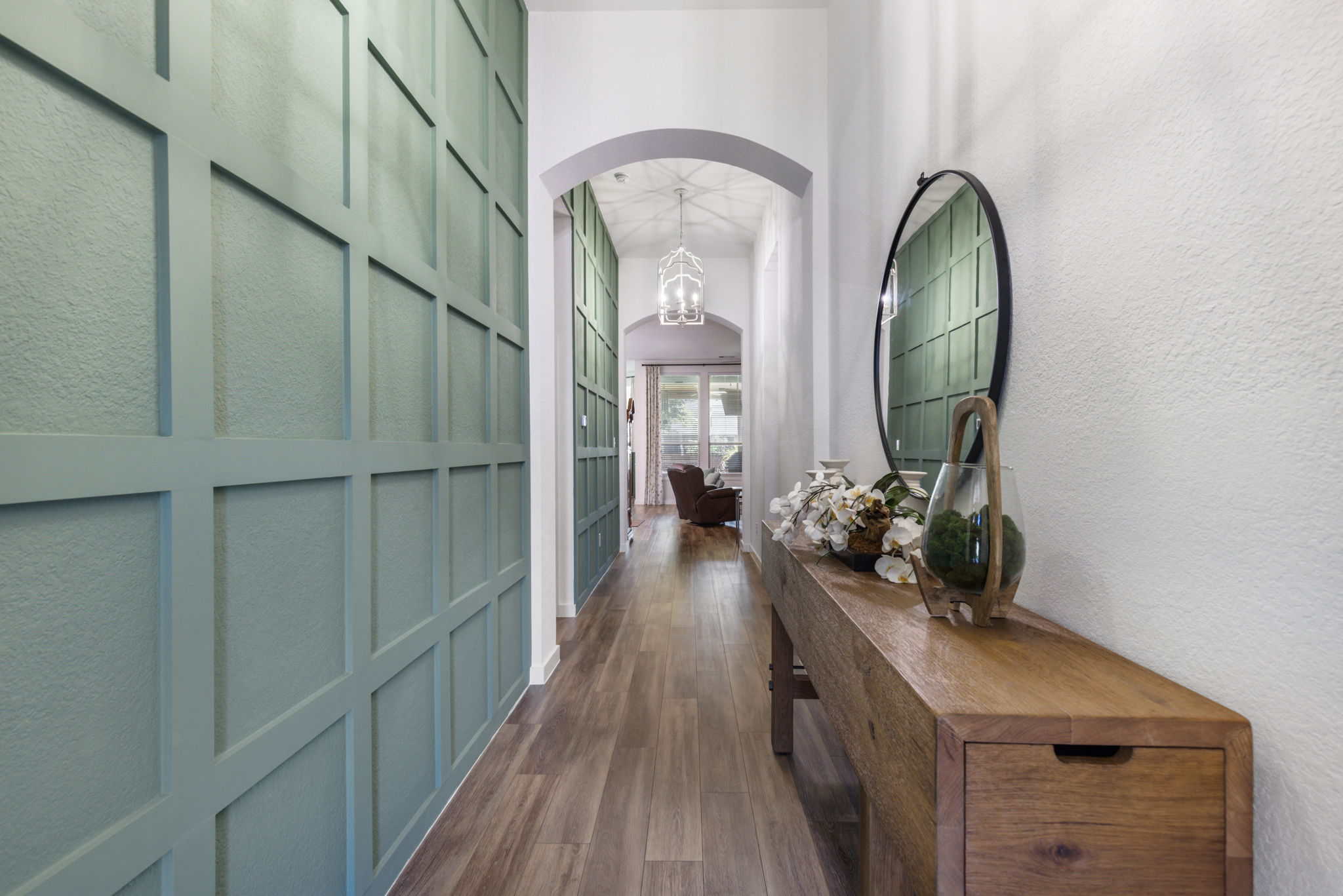 Stylish hallway design with decorative wall paneling and natural wood accents Modern hallway with green paneled wall and wooden console table