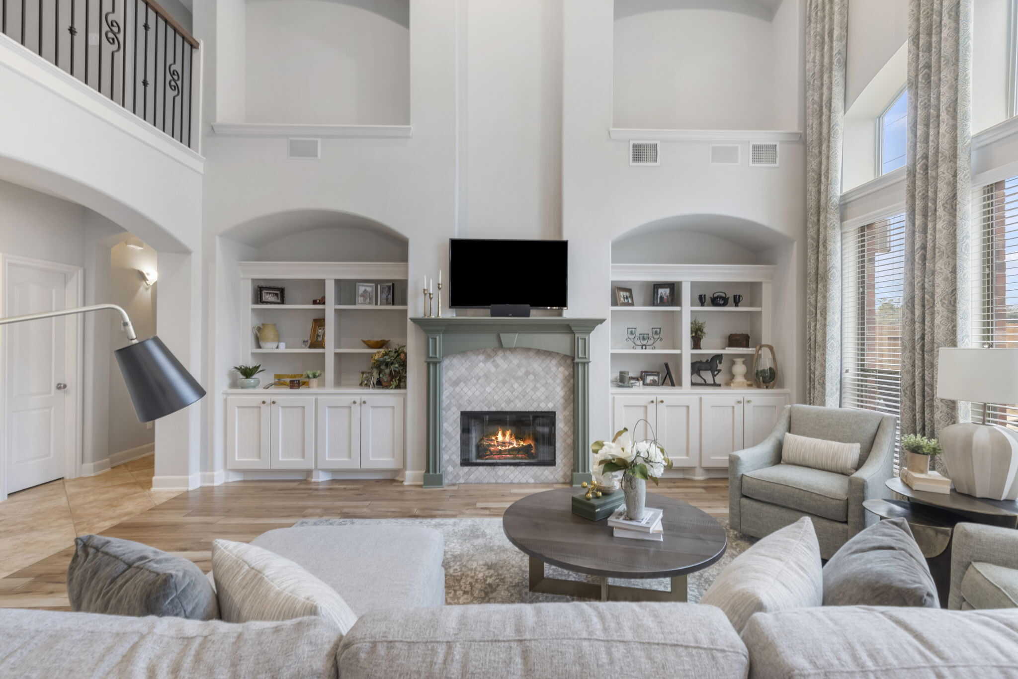 Modern living room design with fireplace and built-in shelving Bright living room with a fireplace, built-in shelves, and large windows with elegant curtains