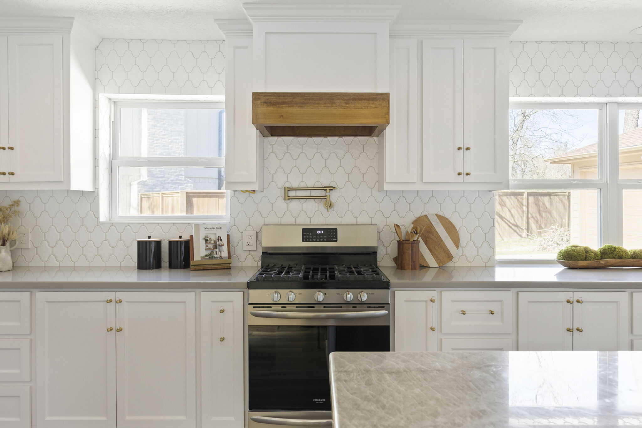 Modern kitchen with white cabinets, stainless steel stove, and patterned backsplash in Woodlands, TX