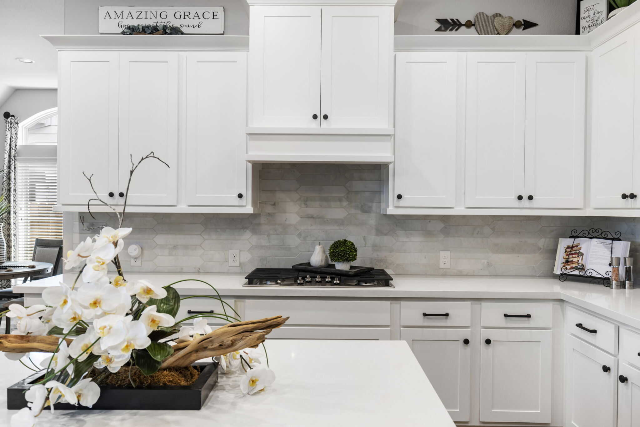 Bright kitchen with shaker cabinets, white countertops, and decorative orchid centerpiece