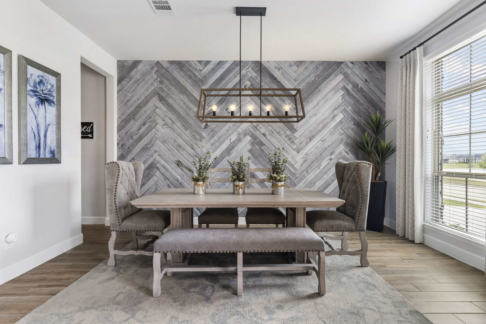 Contemporary dining room with rustic wood wall and modern chandelier Stylish dining room with a wood herringbone accent wall and upholstered chairs