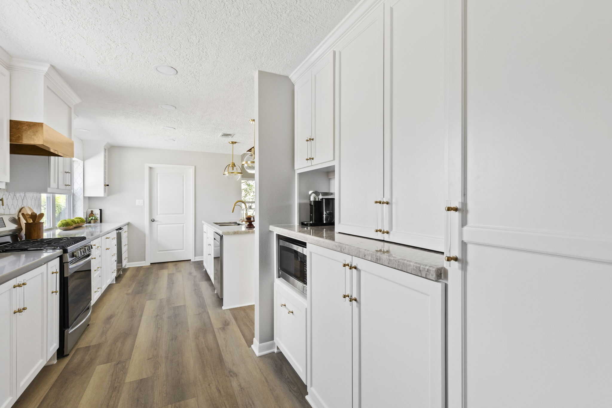 Spacious kitchen with white cabinetry, gold hardware, and marble countertops
