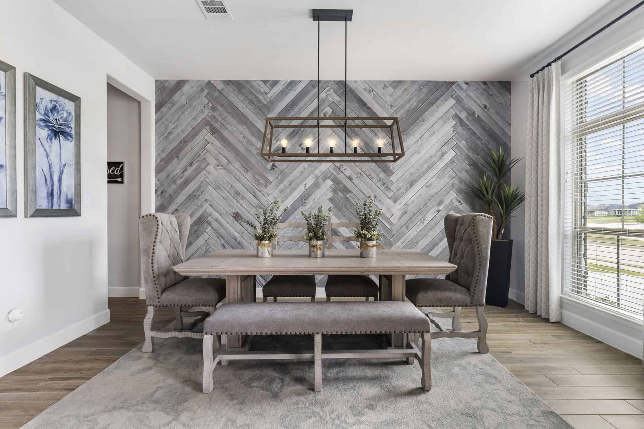 Elegant dining room with herringbone feature wall and contemporary decor Modern dining room with herringbone accent wall, upholstered chairs, and rectangular chandelier.