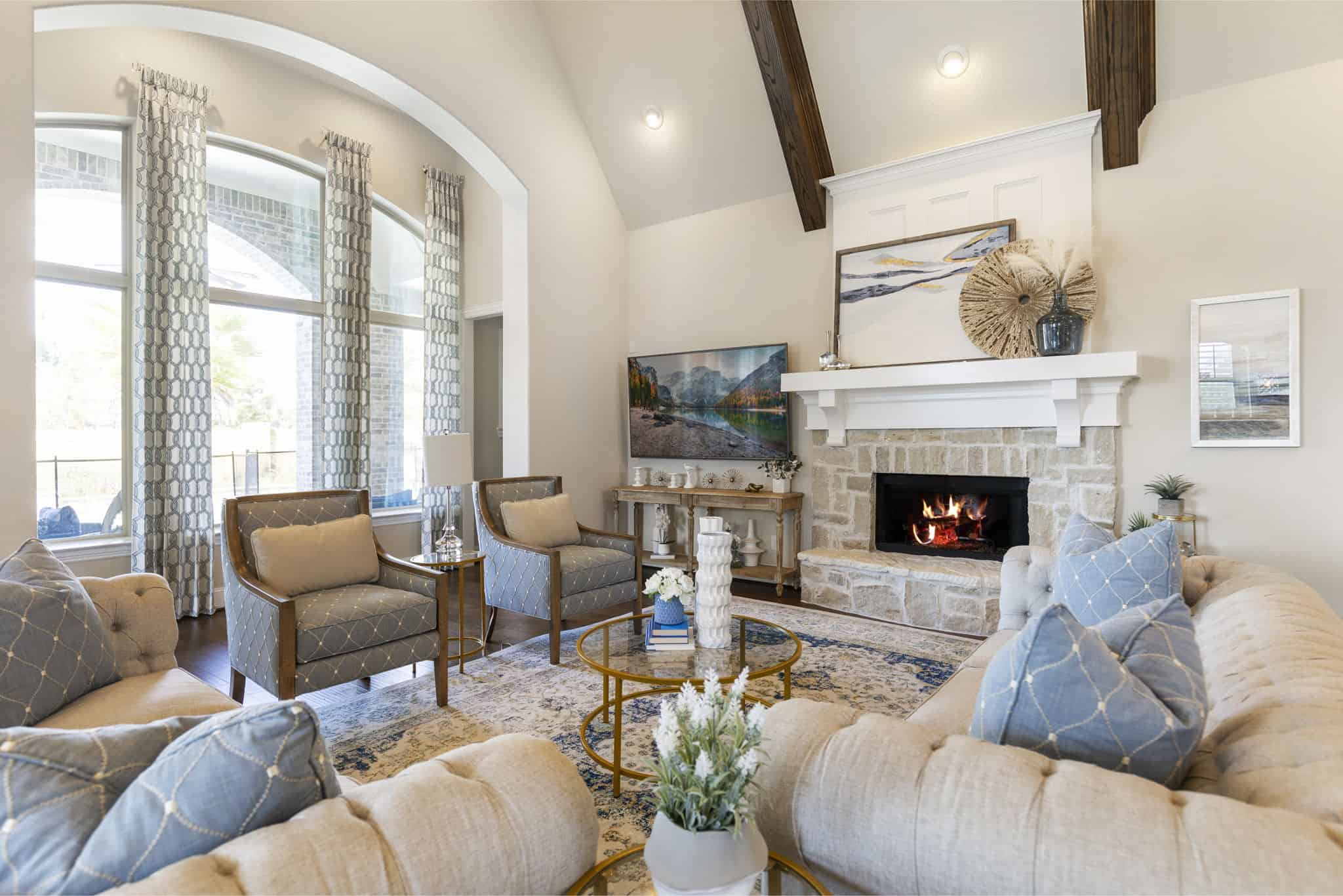 Sophisticated living space with stone fireplace and stylish decor Elegant living room with stone fireplace, vaulted ceilings, and blue upholstered chairs