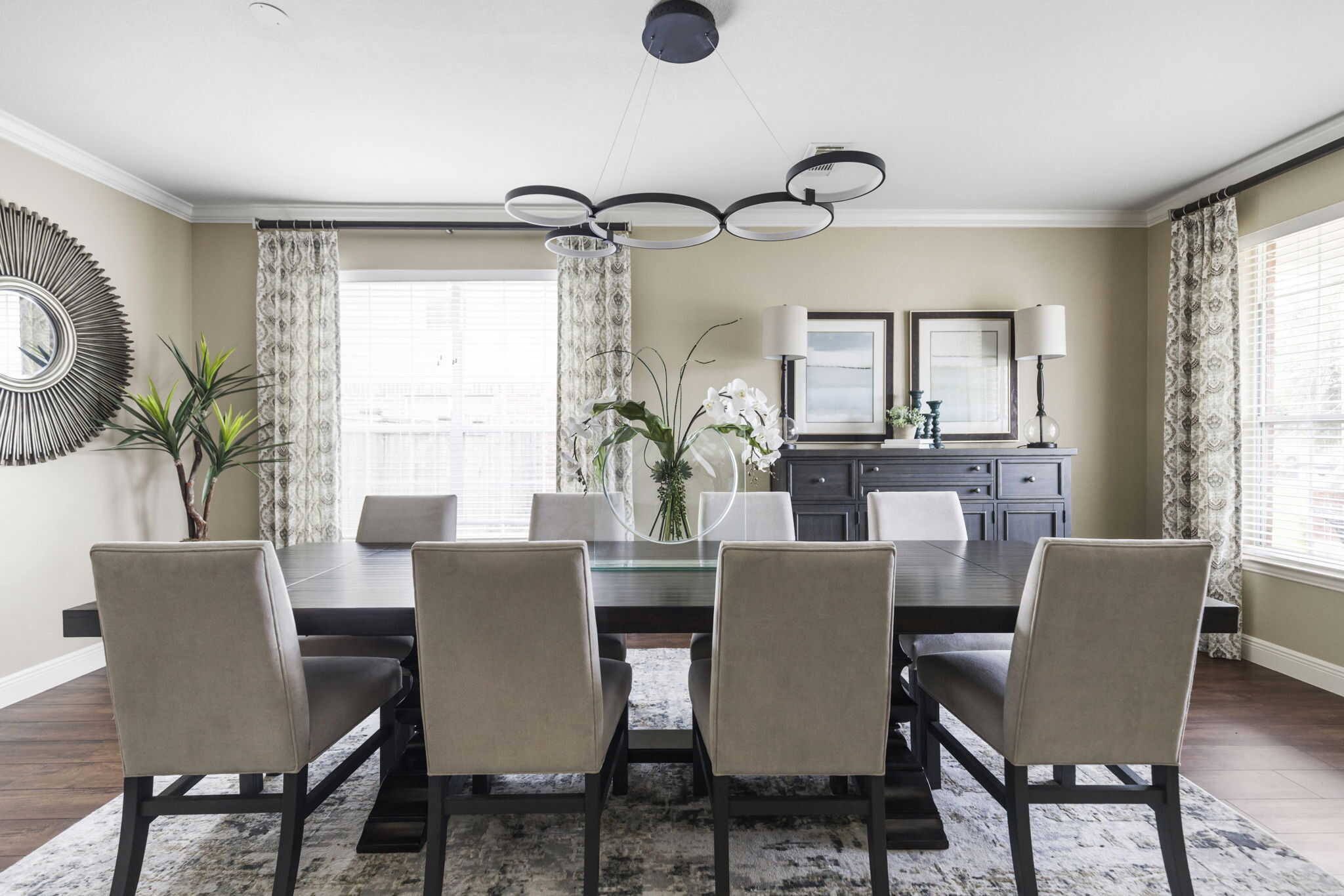 Dining room with custom patterned drapery panels, upholstered dining chairs, and modern chandelier