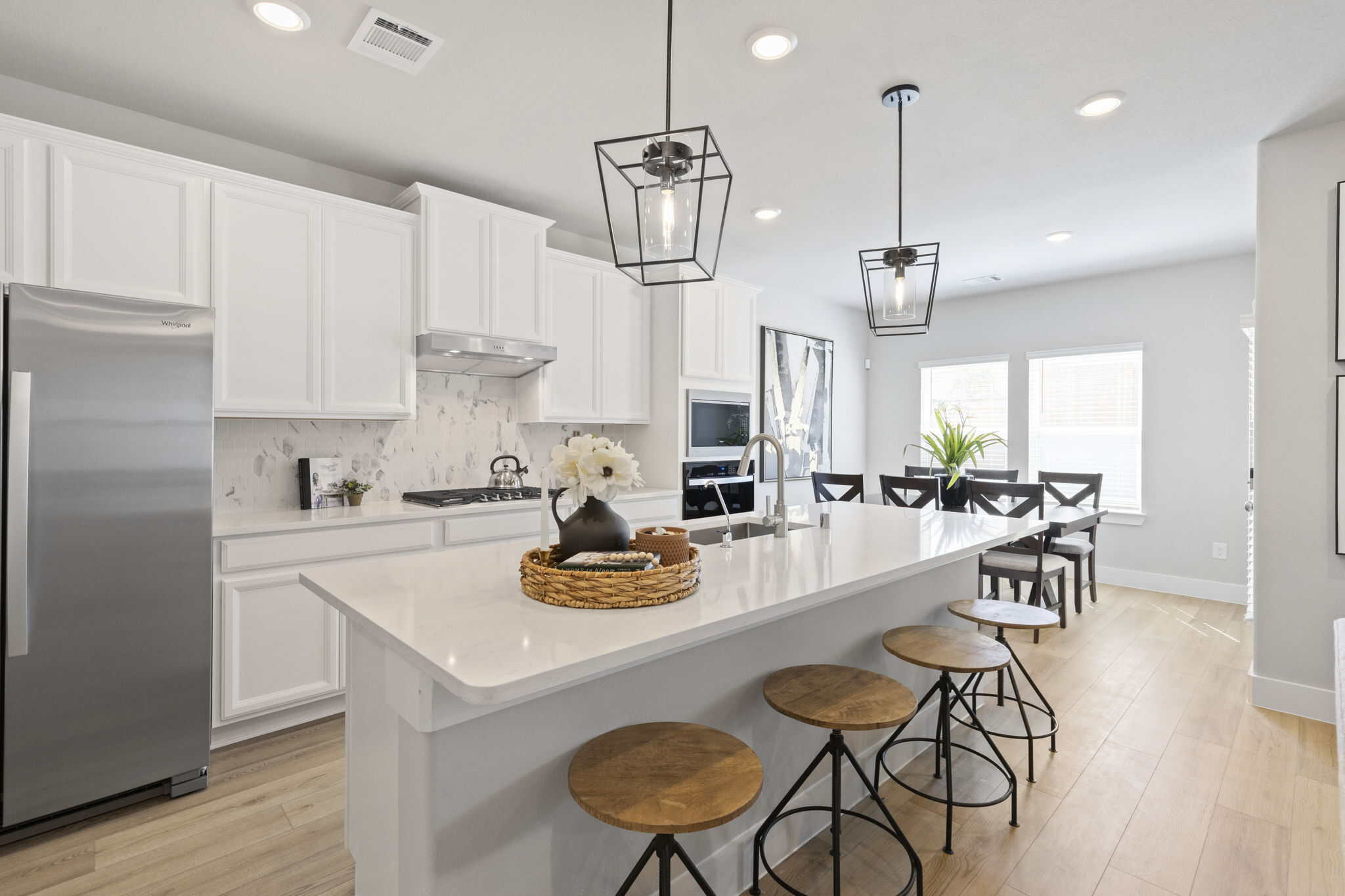 Modern white kitchen with large island, pendant lighting, and bar seating
