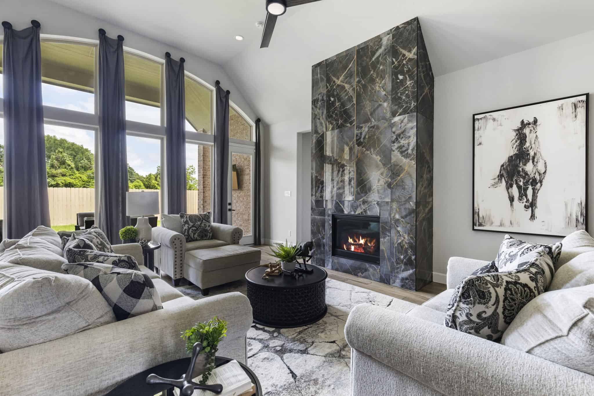 Elegant living room with custom drapery panels, neutral sofa, accent chairs, and fireplac