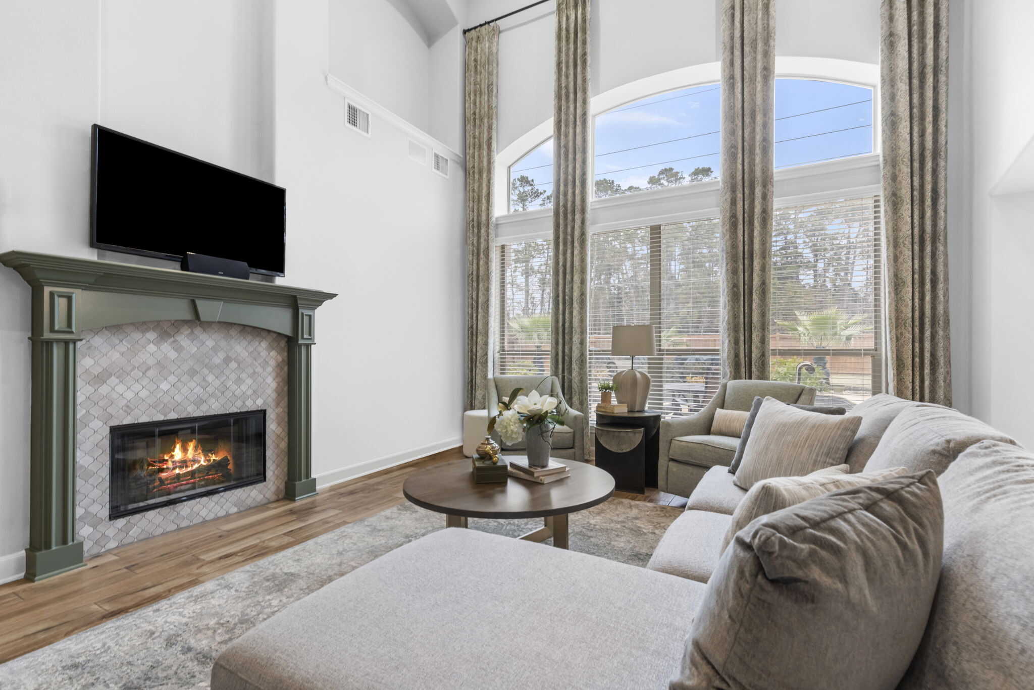 Living room with fireplace, seating area, and tall arched window