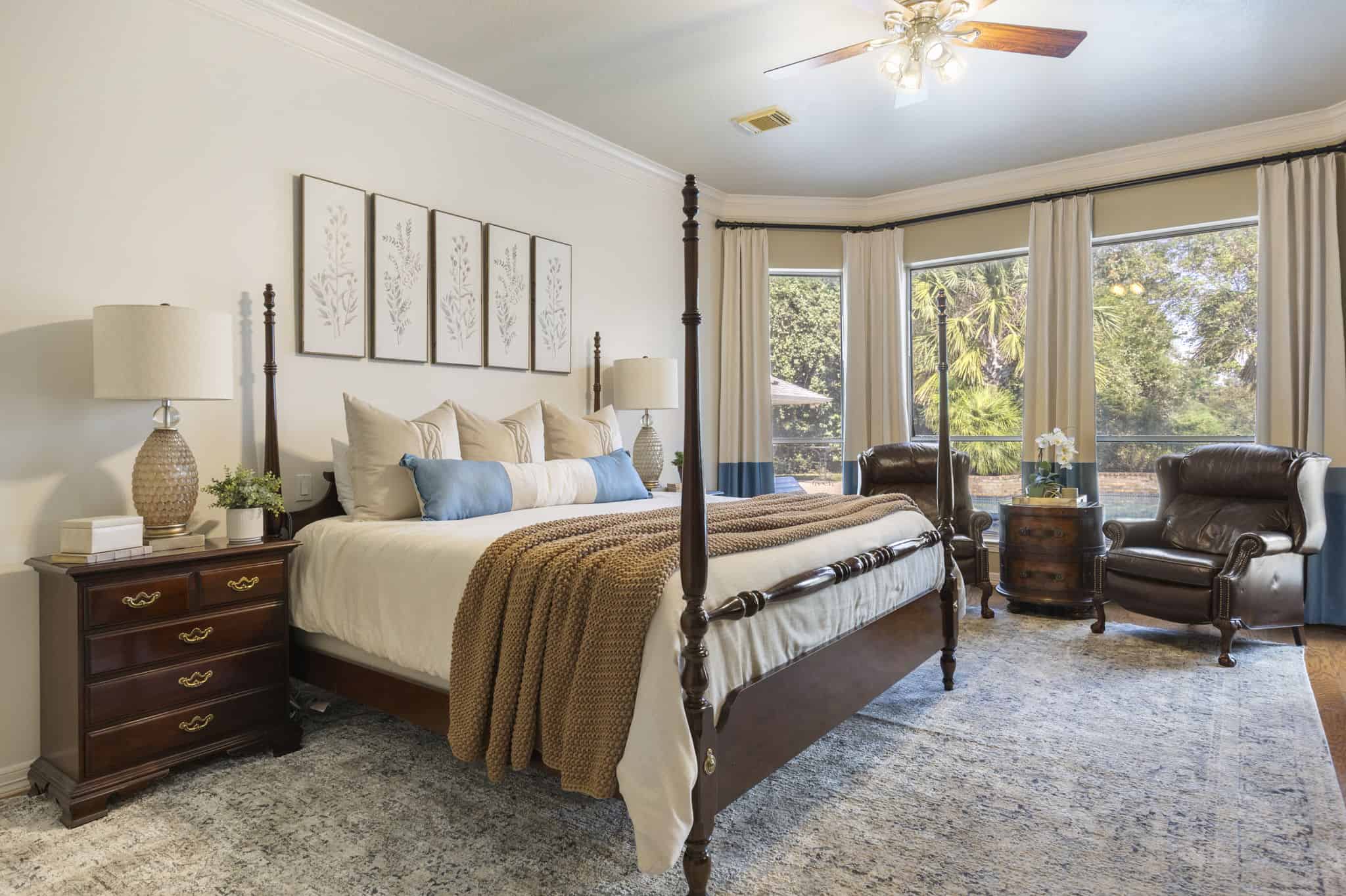 Primary bedroom with custom drapery, four-poster bed, and coordinated seating area