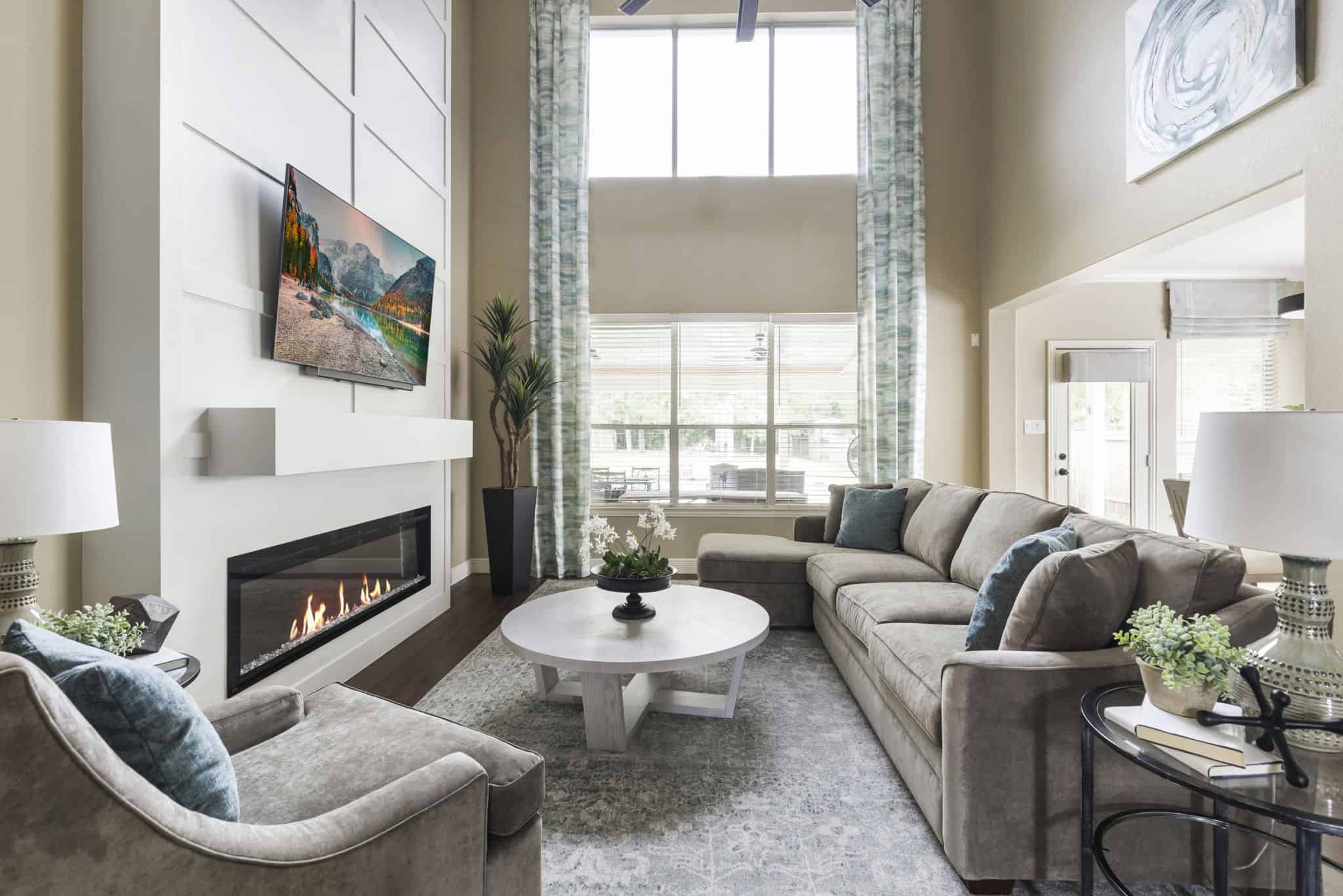 Living room with fireplace, sectional sofa, coffee table, and large windows