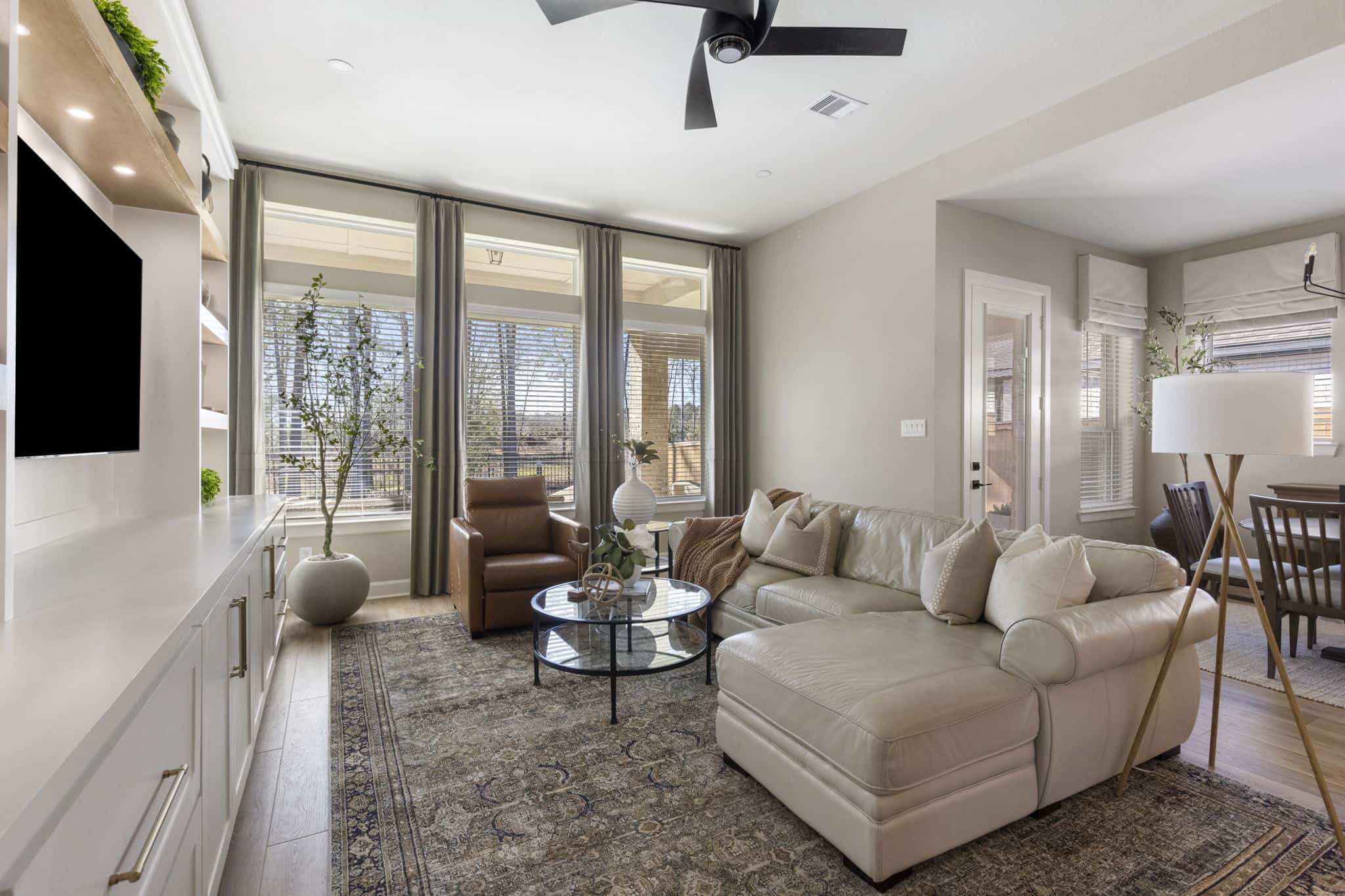 Living room with custom drapery, sectional sofa, and built-in media cabinetry