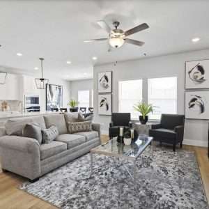 After Renovation – Open Concept Living Room and Kitche Modern open concept living room after renovation with neutral sofa, accent chairs, coffee table, wall art, and bright kitchen in the background