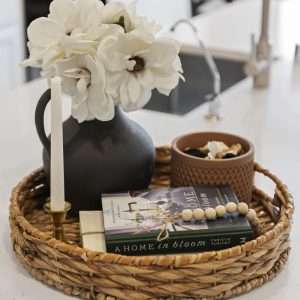 After Renovation – Styled Kitchen Tray Decor Styled kitchen tray with flowers in a black vase, candle, decorative bowl, and book on a white countertop