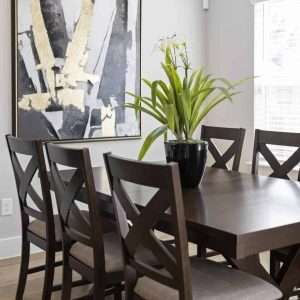 After Renovation – Dining Area with Modern Artwork Dining room after renovation featuring dark wood table and chairs, large abstract wall art, and plant centerpiece by the window