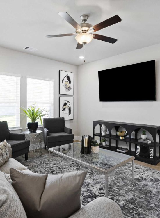 After Renovation – Cozy Living Room with TV and Neutral Decor Modern living room after renovation with neutral sofa, accent chairs, wall-mounted TV, and decorative shelving in a bright open space