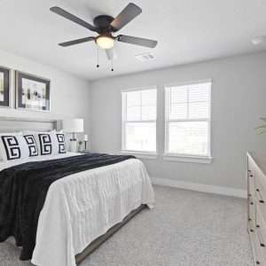 After Renovation – Bright Modern Bedroom with Neutral Decor Bright bedroom after renovation with white bedding, black accent throw, wall art above bed, and natural light from windows