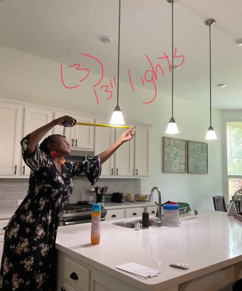 Kitchen Renovation Planning – Measuring Pendant Light Height Woman measuring pendant light height above a kitchen island during renovation planning in a bright modern kitchen
