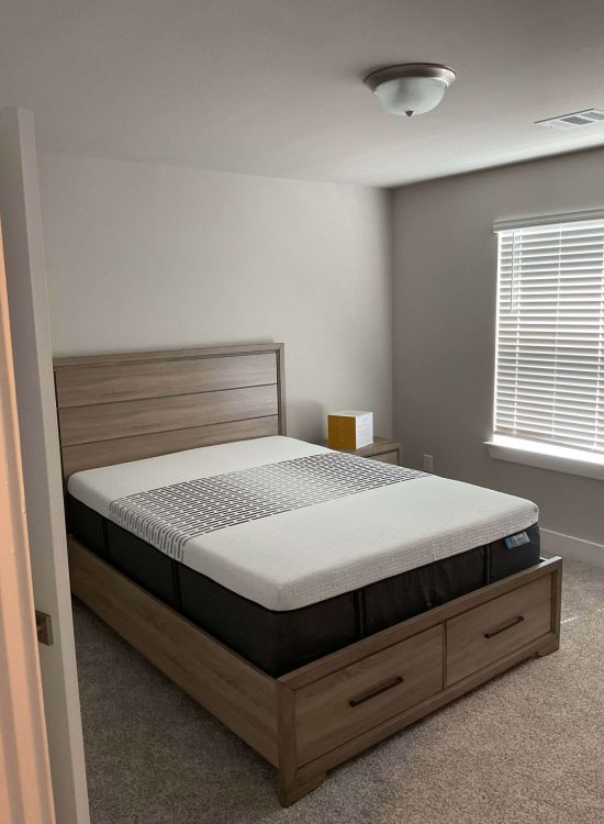Minimalist Bedroom with Warm Wood Accents Modern minimalist bedroom with wood platform bed with drawers, neutral color palette, soft carpet, and natural light from window