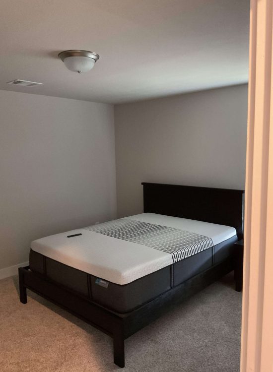 Before Renovation – Simple Bedroom with Basic Setup Bedroom before renovation with a simple bed, mattress, neutral walls, and minimal furnishings