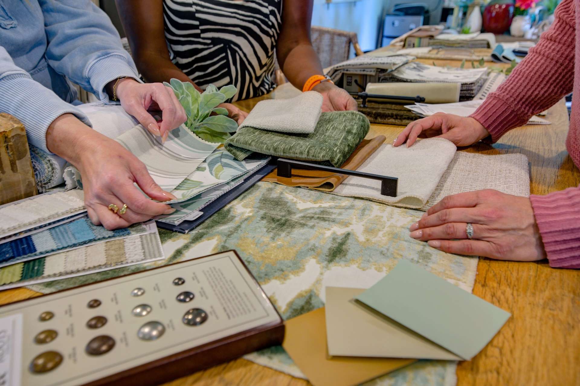Design on a Dime Interiors design team selecting tile, fabric, and hardware finishes at the studio table