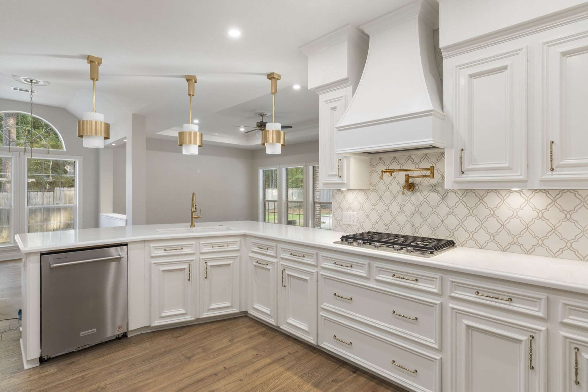 All-white kitchen with brass pot filler and arabesque tile backsplash