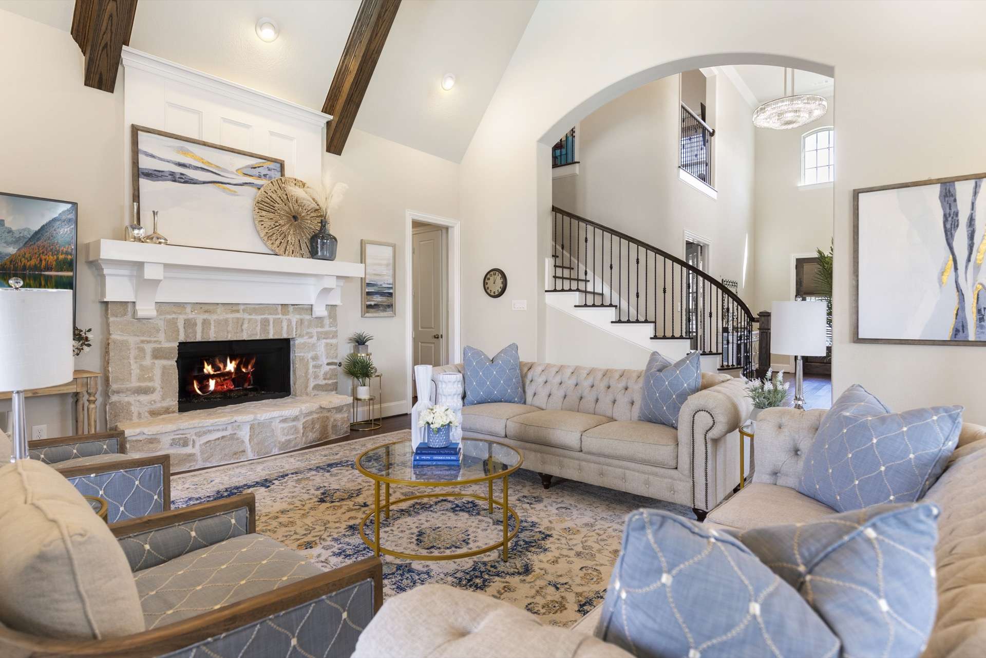 Grand two-story living room with stone fireplace and curved staircase